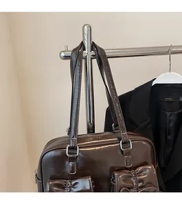 Detail of dark brown tote bag with glossy finish and dual decorative bow front pockets