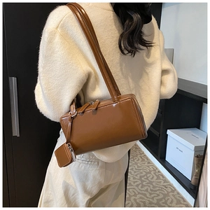 Detail of a brown glossy leather tote bag with shoulder straps and a mini coin purse