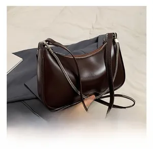 Detailed view of dark brown leather underarm bag with gold chain and NO FILTER text