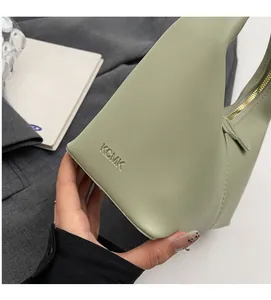Detail of light green leather handbag showing embossed logo and golden metal zipper