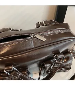 Detail of dark brown vintage oil wax leather handbag with silver zipper and white stitching