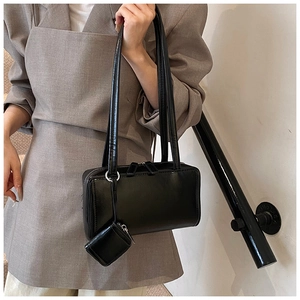 Detail of black glossy tote bag with dual handles and side mini coin purse charm