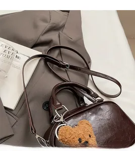 Detail of vintage brown shoulder bag with adjustable strap and plush bear charm