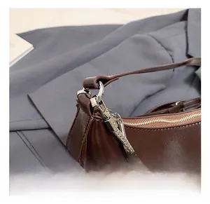 Detail of dark brown leather handbag with silver metal hooks and chain decoration