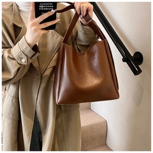 Minimalist deep brown leather bucket bag styled with a trench coat for a chic look
