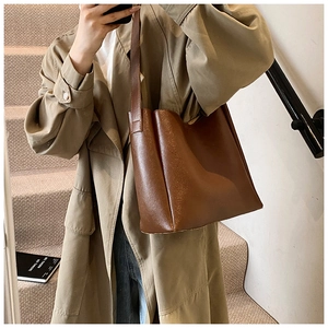 Detailed view of deep brown leather tote bag worn with a khaki trench coat