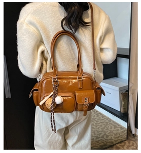 Detail view of a glossy caramel brown bowling bag with vintage pockets and baseball charms