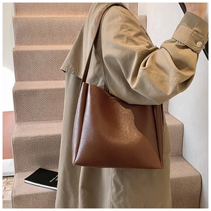 Brown minimalist leather bucket bag styled with a khaki trench coat for autumn fashion