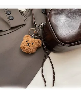 Detail of brown glossy oil wax leather bag with woven strap and a plush bear charm