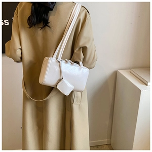 Rear view of a white rectangular shoulder bag in glossy faux leather on a trench coat