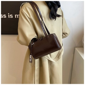Detail of dark brown glossy patent leather tote bag with slim double shoulder straps