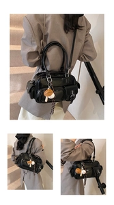 Detail of black glossy PU handbag with multiple pockets and a baseball glove pendant