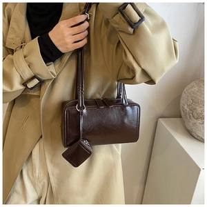 Detail of dark brown glossy tote bag featuring a matching mini zip pouch attachment