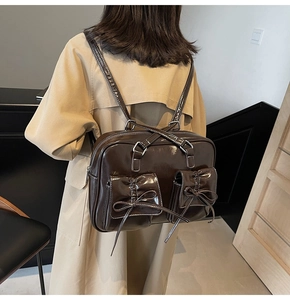 Dark brown shiny leather backpack with bow-decorated pockets worn by a model
