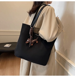 Gros plan du sac fourre-tout en nylon noir avec charm teckel et bandoulières en cuir chic
