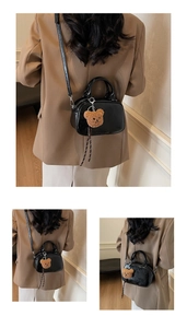 Detail of black patent leather bag featuring a cute brown plush bear keychain accessory