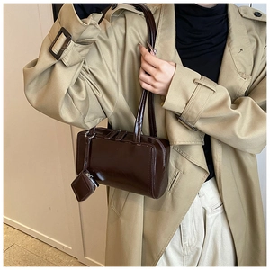 Detail of dark brown glossy tote bag with a matching mini pouch charm and shoulder strap