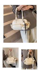 Detailed cream-colored bowling bag with multiple pockets and a baseball charm