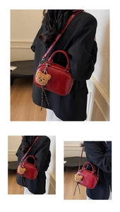 Detail of red glossy patent leather handbag with a cute brown plush bear keychain
