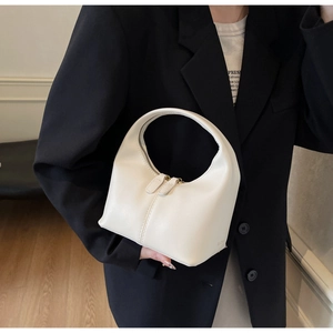Detailed view of cream PU leather handbag featuring a unique curved shape and dual zipper closure