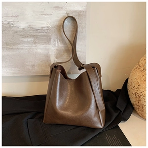 Detailed side view of the dark brown minimalist bucket bag with adjustable wide shoulder strap