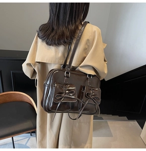 Detail of vintage brown patent leather handbag with bow pockets and contrast stitching