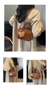 Detail of a brown leather shoulder bag with a plush bear charm and glossy finish