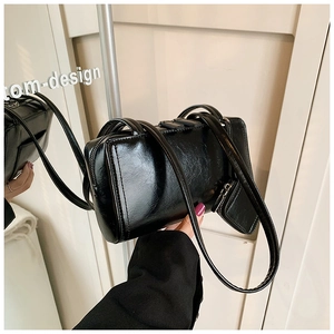 Detail of black glossy tote bag with pleated texture and stylish small charm pouch