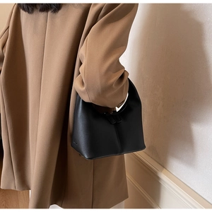 Minimalist black matte leather hobo bag paired with a classic camel cashmere coat