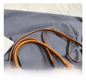 Detail of brown glossy leather bag showing neat stitching and metallic buckles