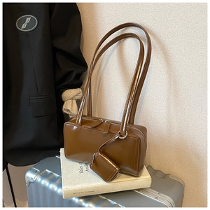 Caramel brown glossy leather tote bag with mini pouch detail on a silver suitcase