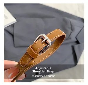 Close-up of adjustable brown leather shoulder strap with silver metal buckle on tote bag