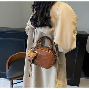 Gros plan d'un sac bowling marron caramel avec texture vintage et breloque en forme d'ours