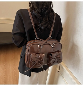 Detail of dark brown leather backpack with bow drawstrings and decorative flap pockets