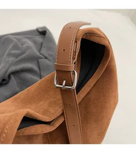 Detail of caramel suede shoulder bag showing silver metal buckle and textured leather strap