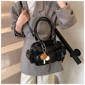 Detail of glossy black bowling bag featuring multiple pockets and baseball glove charm