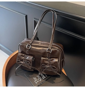 Detail of dark brown glossy leather tote with ribbon pockets on a vintage wooden stool