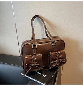 Detail of dark brown glossy leather tote bag featuring bow accents and silver hardware