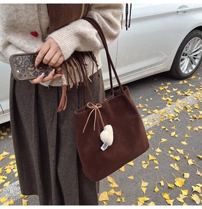 Close-up of deep brown matte suede tote bag with heart charm and bow details
