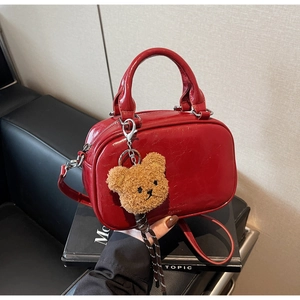 Détail du sac à main en cuir ciré rouge avec pendentif ourson et bandoulière chic