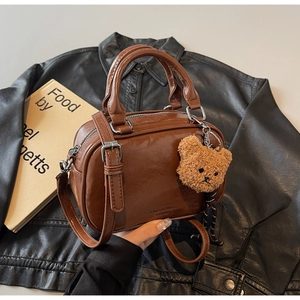 Détail du sac bowling rétro en cuir marron avec pendentif ours et bandoulière réglable