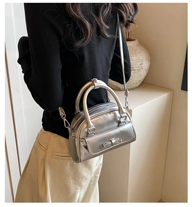 Metallic silver handbag with bow detail on a minimal tabletop beside a ceramic vase
