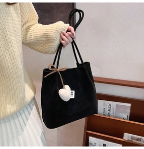 Detail of black matte tote bag featuring a plush heart charm and long shoulder straps