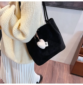 Detail of black suede tote bag with heart plush charm and minimalist shoulder strap