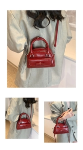 Detailed view of red glossy Boston bag with bow decoration and detachable strap