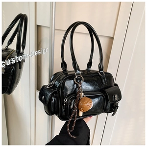 Macro detail of black wrinkled patent leather bowling bag with silver zipper and charm