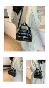 Detail showing shiny black patent leather shell bag with decorative bow and top handle
