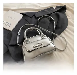 Detailed view of silver mini Boston bag with bow clasp and adjustable shoulder strap