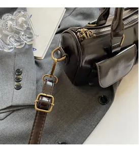 Close-up of deep brown glossy leather cylinder bag with vintage bronze hardware