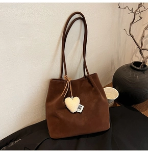 Detail of dark brown faux suede tote bag with plush heart charm and stay dry tag
